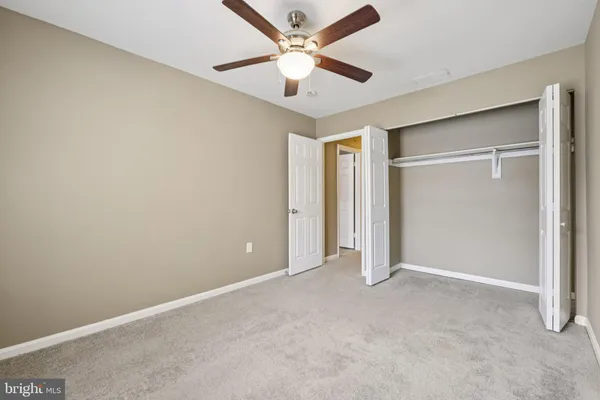 an empty room with closet and a ceiling fan