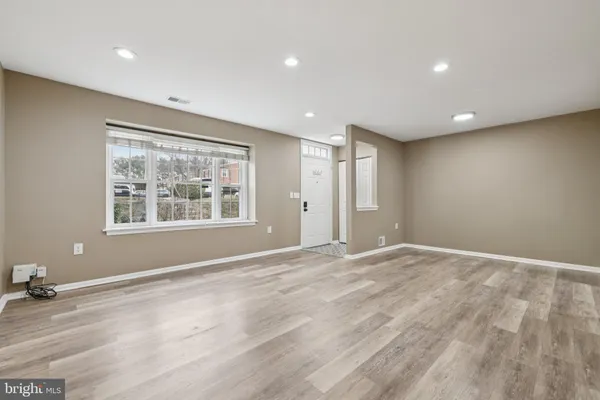 a view of an empty room with window and wooden floor