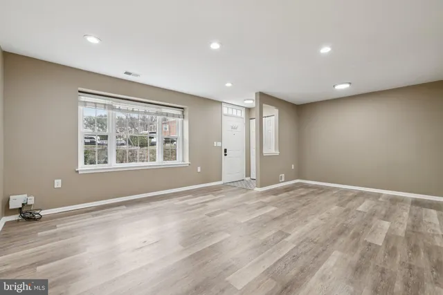 a view of an empty room with window and wooden floor
