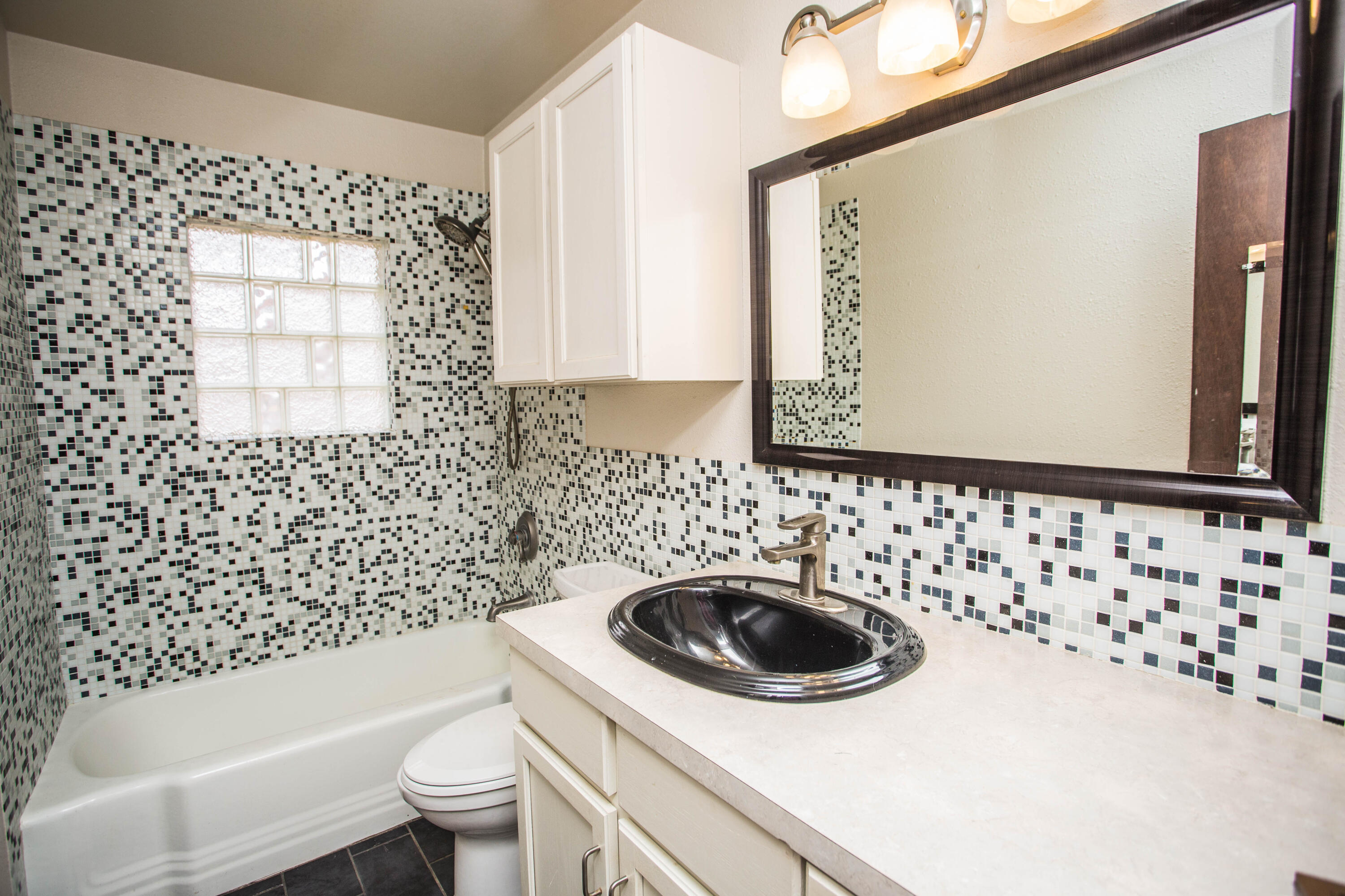 4932 9th Street Lubbock, TX 79416 - Photo 15 of 29 a bathroom with a sink a toilet and a mirror