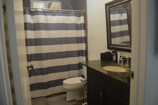 a bathroom with a granite countertop toilet a sink and a mirror