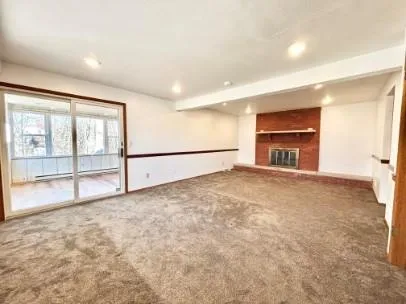 a view of an empty room with a fireplace and a window
