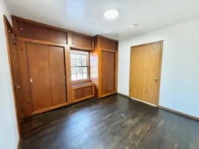 an empty room with wooden floor and windows with curtains