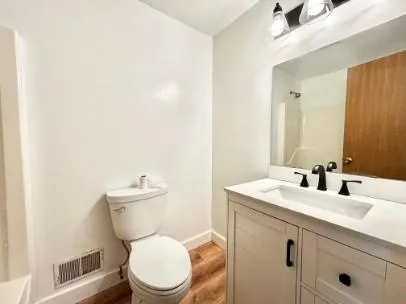 a bathroom with a toilet sink vanity and mirror
