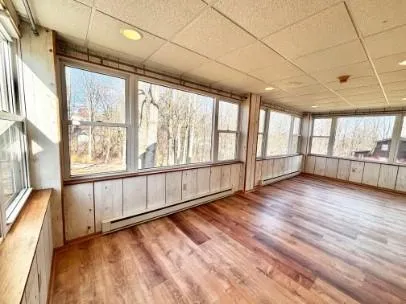 a view of an empty room with wooden floor and a window