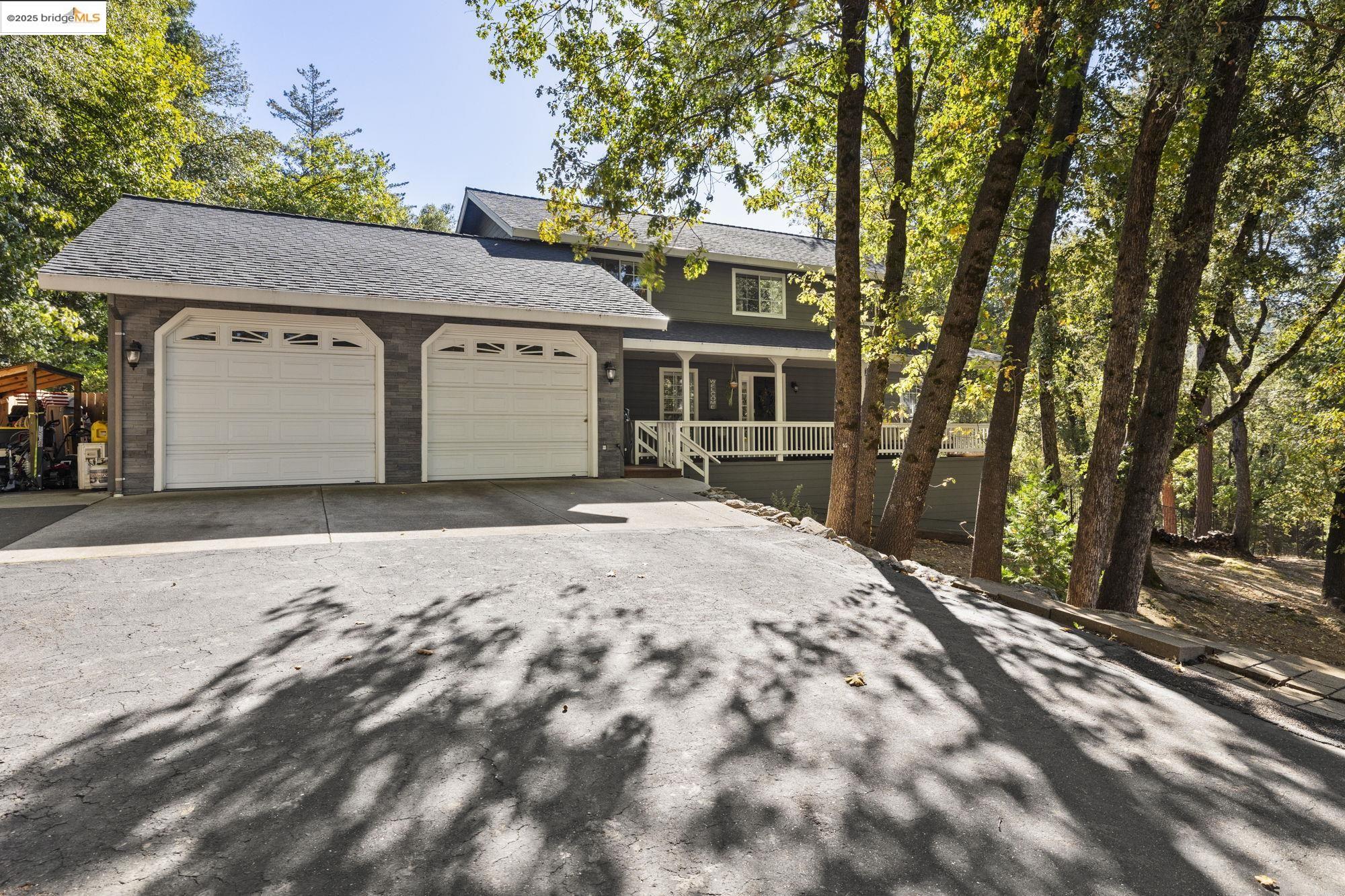 View of front of home featuring driveway, a porch, roof with shingles, and an attached garage
