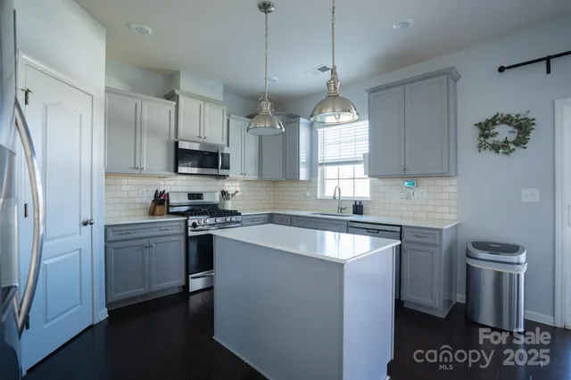 a kitchen with stainless steel appliances granite countertop a sink a stove a refrigerator cabinets and a window