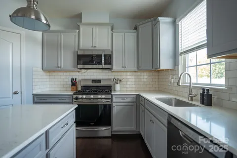 a kitchen with granite countertop white cabinets white stainless steel appliances and sink