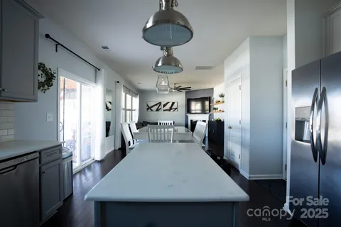 a kitchen with stainless steel appliances granite countertop a refrigerator a sink dishwasher a dining table and chairs with wooden floor