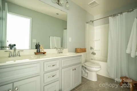 a bathroom with a double vanity sink toilet mirror and shower