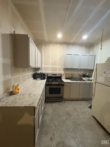 a kitchen with granite countertop a stove sink and cabinets