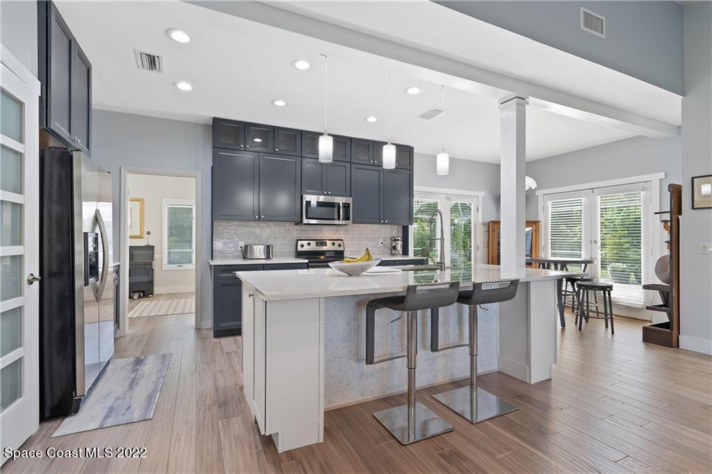 Undisclosed Address Vero Beach, FL 32963 - Photo 2 of 36 a kitchen with stainless steel appliances kitchen island granite countertop a stove a refrigerator a sink a dining table and chairs with wooden floor