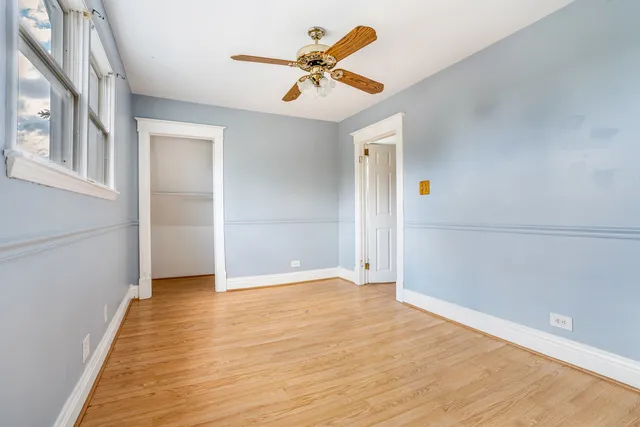 a view of an empty room with window and a ceiling fan
