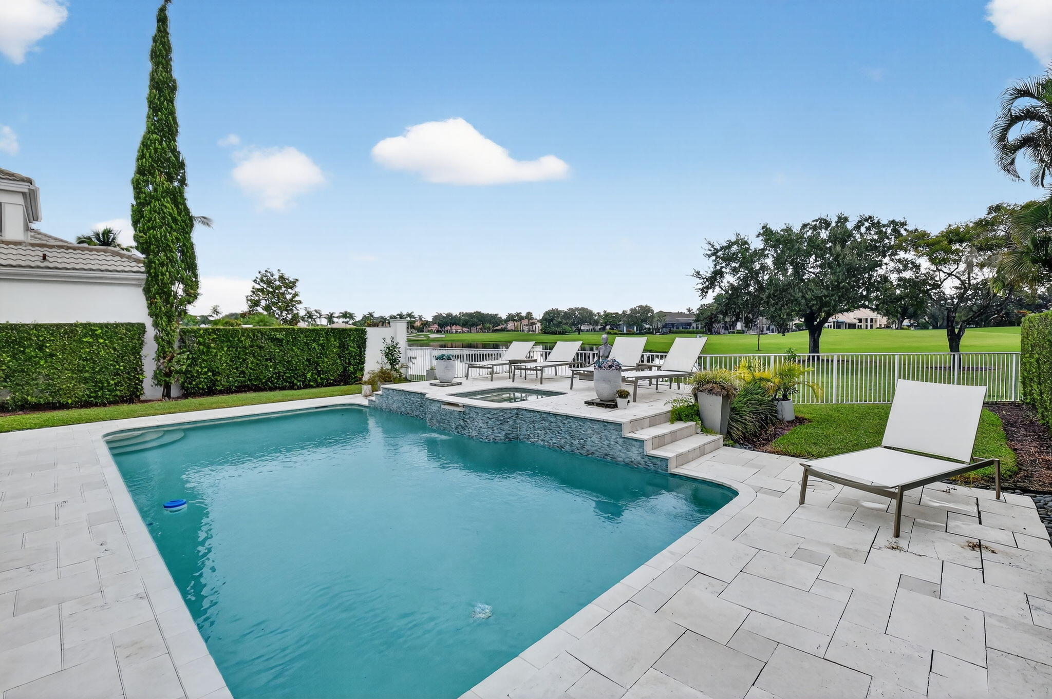2563 Northwest 63rd Street Boca Raton, FL 33496 - Photo 51 of 65 a view of a swimming pool and lounge chairs in back yard of the house