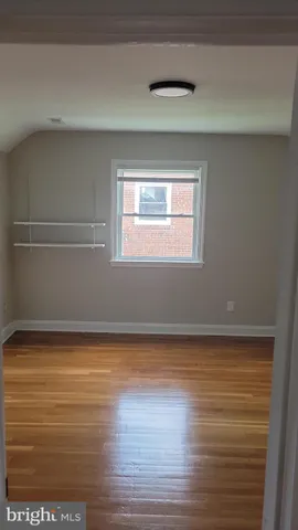 a view of empty room with window and wooden floor