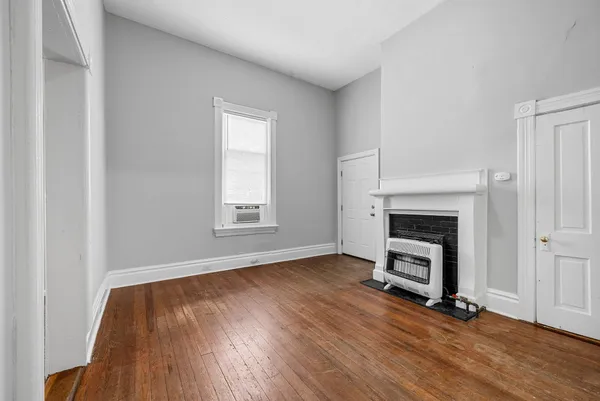 a view of empty room with wooden floor and fireplace
