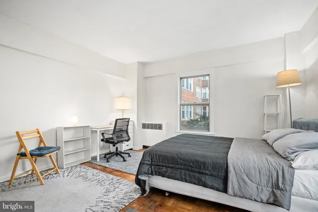 a bedroom with a bed a chair and next to a window