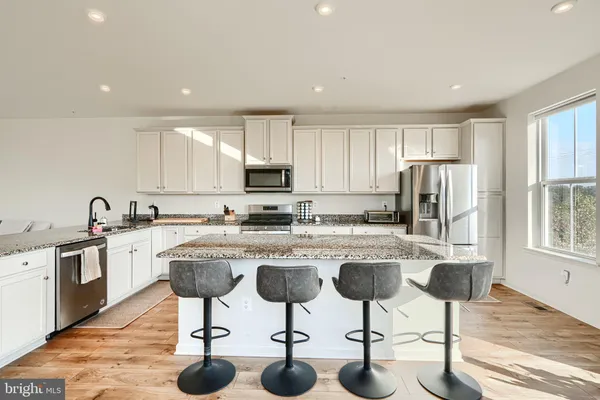 a kitchen with stainless steel appliances granite countertop a table chairs sink and cabinets