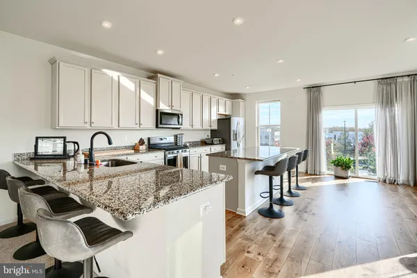 a kitchen with granite countertop a stove a sink a dining table and chairs