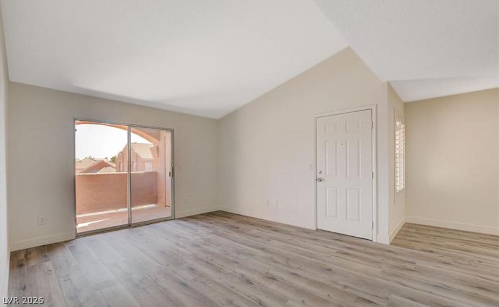 8101 West Flamingo Road, Unit 2014 Las Vegas, NV 89147 - Photo 5 of 13 Vaulted ceilings and wood-style flooring elevate this versatile living space opening to a private balcony.