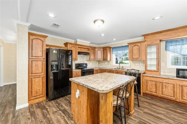 a kitchen with stainless steel appliances granite countertop wooden floor cabinets and stove top oven