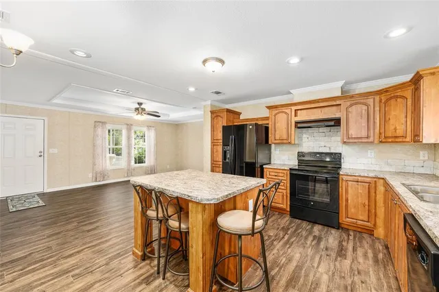 a kitchen with stainless steel appliances granite countertop a stove top oven a sink dishwasher a dining table and chairs with wooden floor