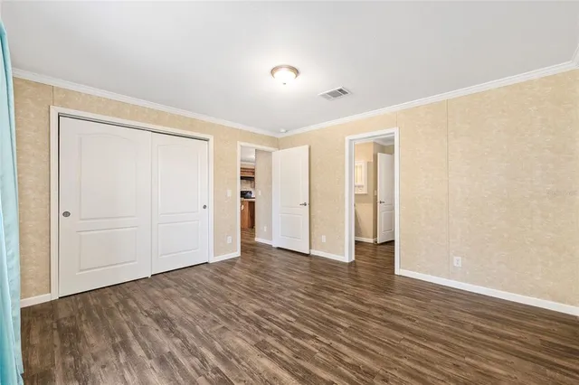 an empty room with wooden floor chandelier fan and windows