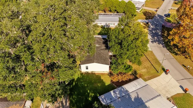 an aerial view of residential houses with outdoor space and trees