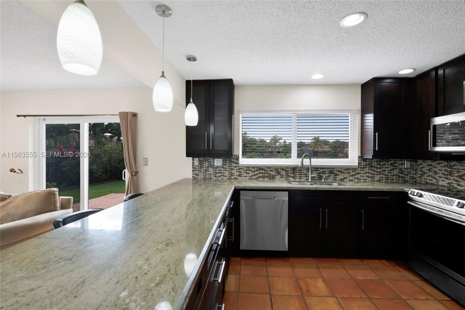 5757 Southwest 113th Avenue Cooper City, FL 33330 - Photo 17 of 48 a kitchen with granite countertop a stove a sink and a refrigerator