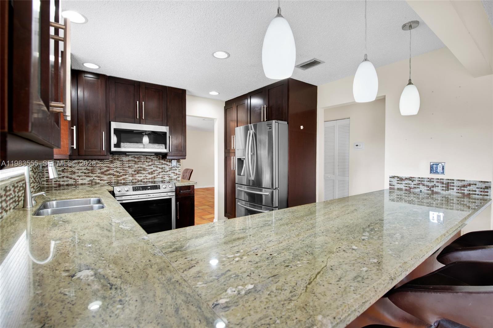 5757 Southwest 113th Avenue Cooper City, FL 33330 - Photo 19 of 48 a kitchen with stainless steel appliances granite countertop a stove refrigerator and microwave