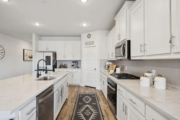 a kitchen with stainless steel appliances granite countertop a sink stove refrigerator and cabinets