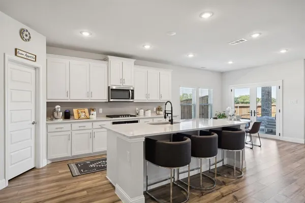a kitchen with stainless steel appliances kitchen island granite countertop a stove a sink a dining table and chairs
