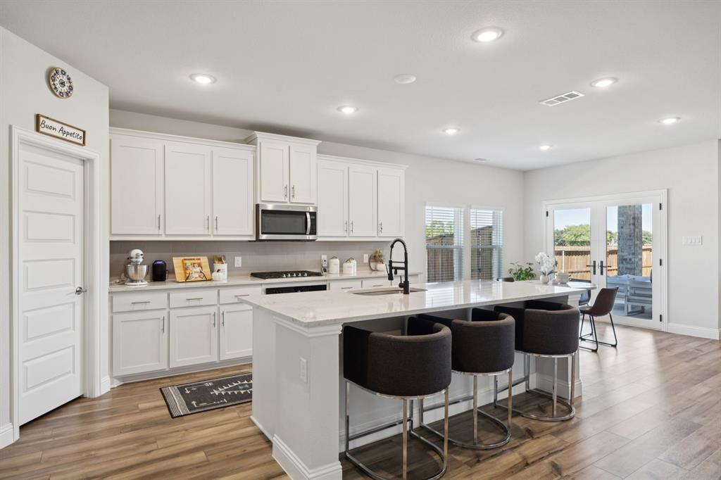 722 Cari Lane Forney, TX 75126 - Photo 7 of 40 a kitchen with stainless steel appliances kitchen island granite countertop a stove a sink a dining table and chairs