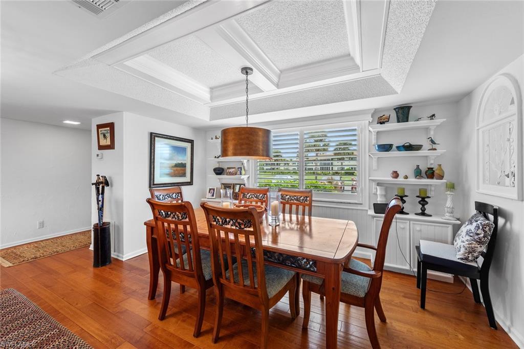 287 Albi Road, Unit 2803 Naples, FL 34112 - Photo 10 of 50 Dining space featuring a raised ceiling, wood-type flooring, a textured ceiling, and ornamental molding