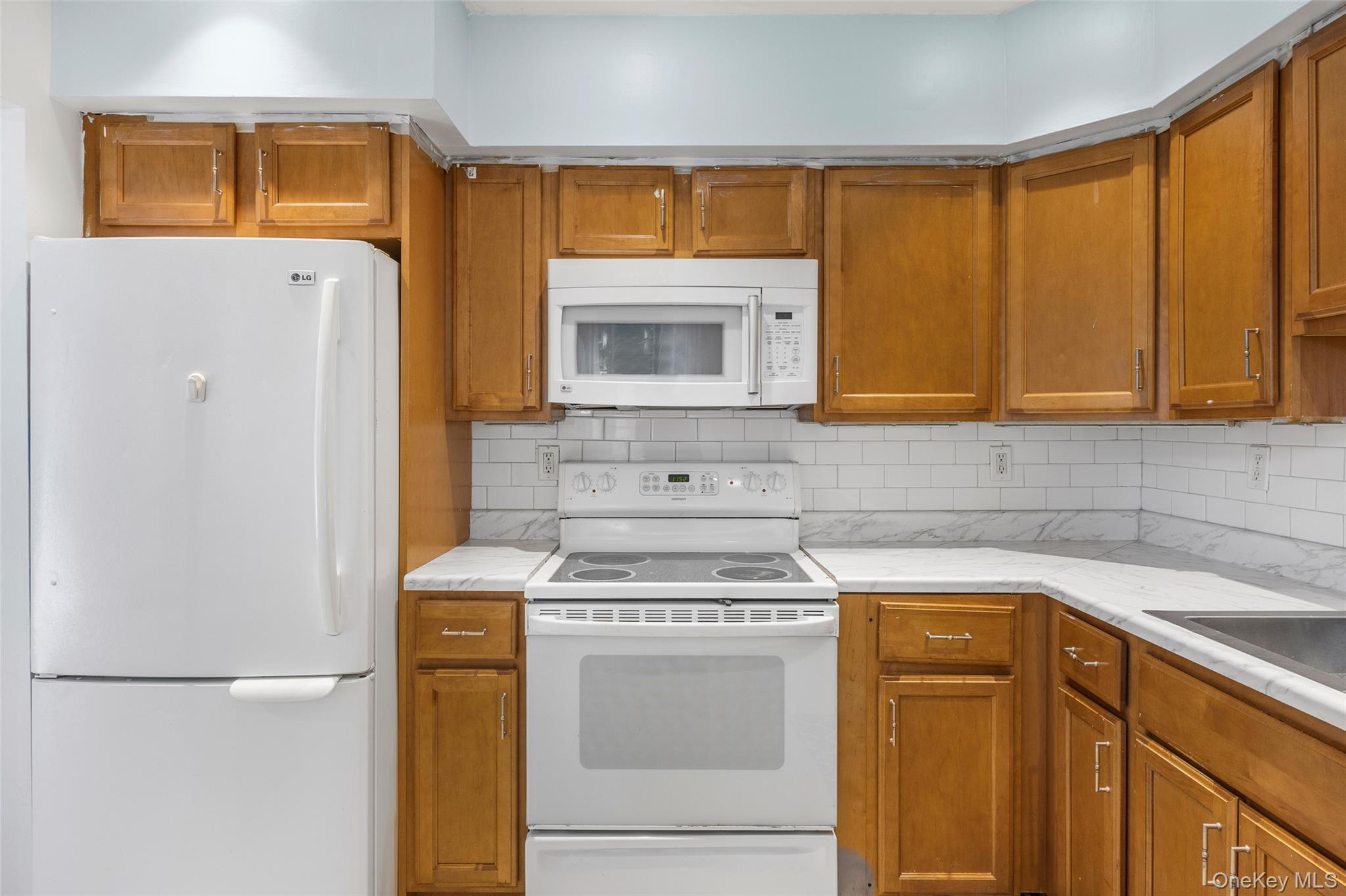 655 Middle Country Road, Unit 1G1 Coram, NY 11727 - Photo 5 of 15 a kitchen with a stove a sink and a refrigerator