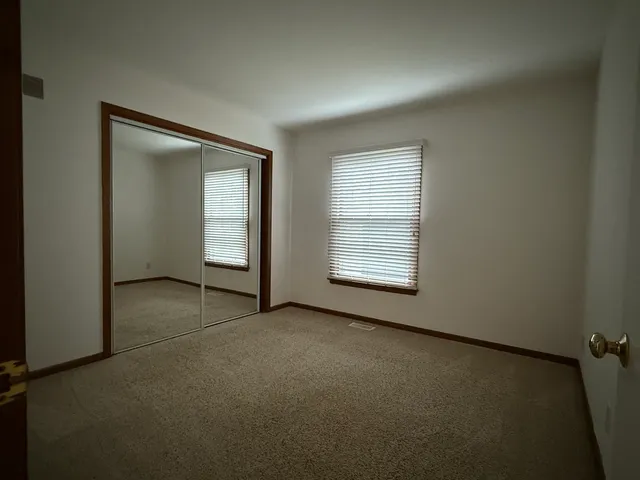 an empty room with chandelier fan and windows