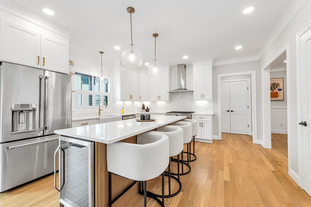 a very nice looking kitchen with a table chairs refrigerator and wooden floor