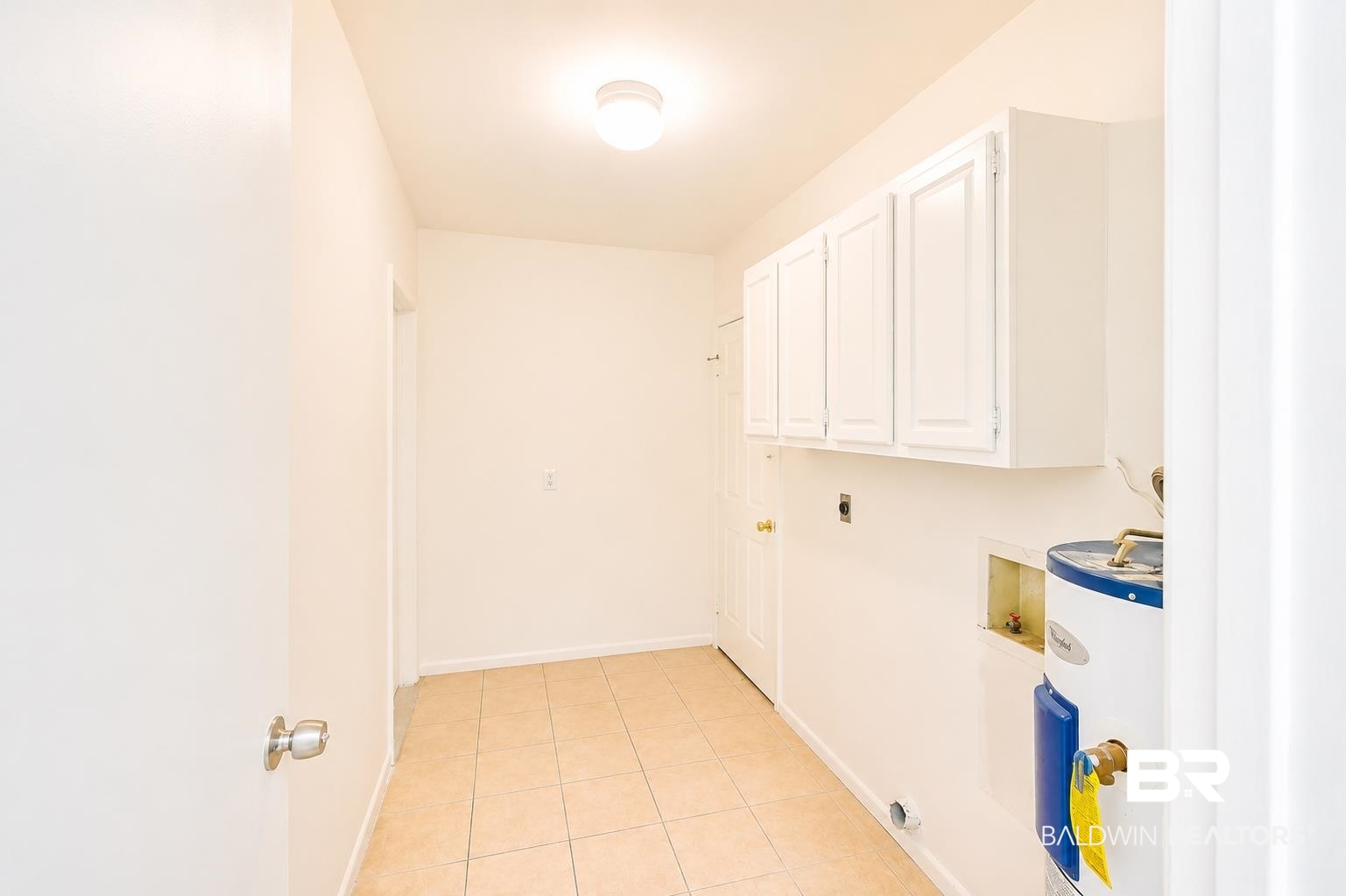 614 East Gate Circle Foley, AL 36535 - Photo 13 of 31 Utility room featuring ceramic tile flooring, white wall cabinets, a ceiling-mounted light fixture, and a water heater