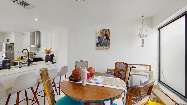 a kitchen with stainless steel appliances a table and chairs in it