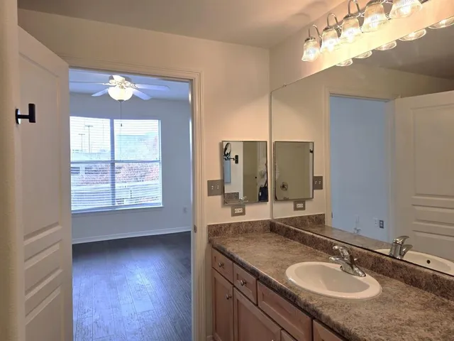a bathroom with a granite countertop sink a large mirror and a window