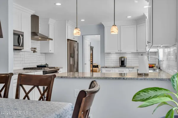 a kitchen with stainless steel appliances granite countertop a stove top oven a sink a dining table and chairs with wooden floor