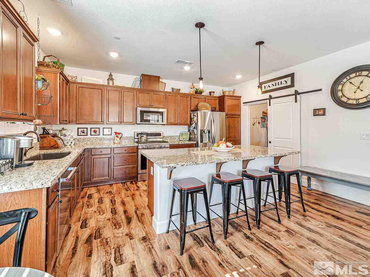 1890 Dark Horse Road, Unit 1062 Reno, NV 89521 - Photo 6 of 19 a kitchen with stainless steel appliances kitchen island granite countertop a table chairs and a stove