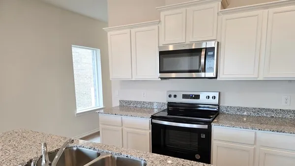 a kitchen with stainless steel appliances granite countertop a stove microwave and sink