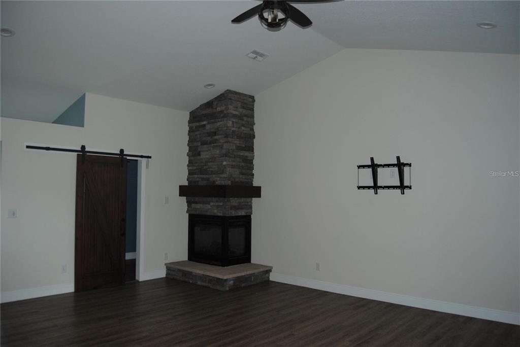 1167 Southeast 63rd Ct Road Ocala, FL 34472 - Photo 8 of 37 a view of an empty room with wooden floor and a fireplace