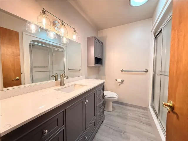a bathroom with a granite countertop sink toilet and mirror