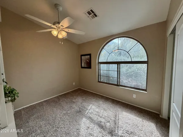 an empty room with a window and a chandelier fan