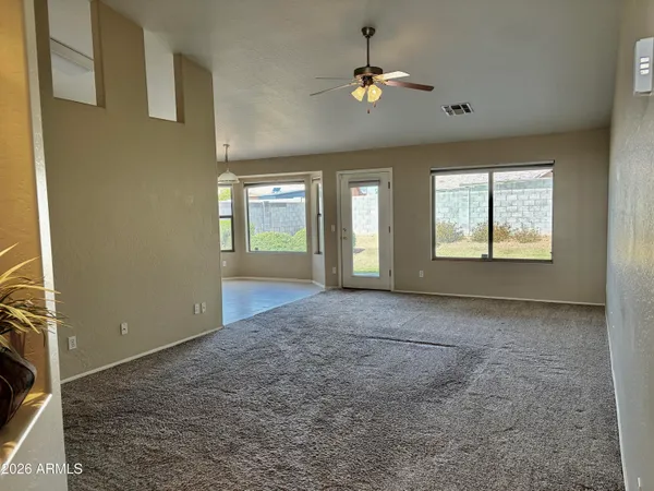 an empty room with chandelier fan and windows
