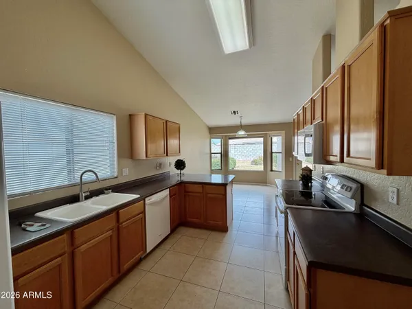 a large kitchen with granite countertop a sink and dishwasher a stove top oven with wooden floor