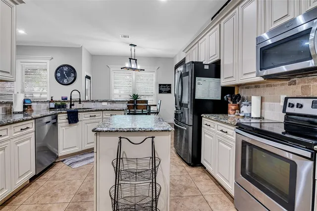 a kitchen with stainless steel appliances granite countertop a stove top oven a sink dishwasher and a refrigerator with wooden cabinets