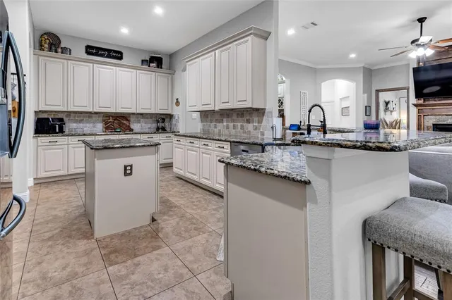 a kitchen with stainless steel appliances granite countertop a stove top oven a sink a dining table and chairs
